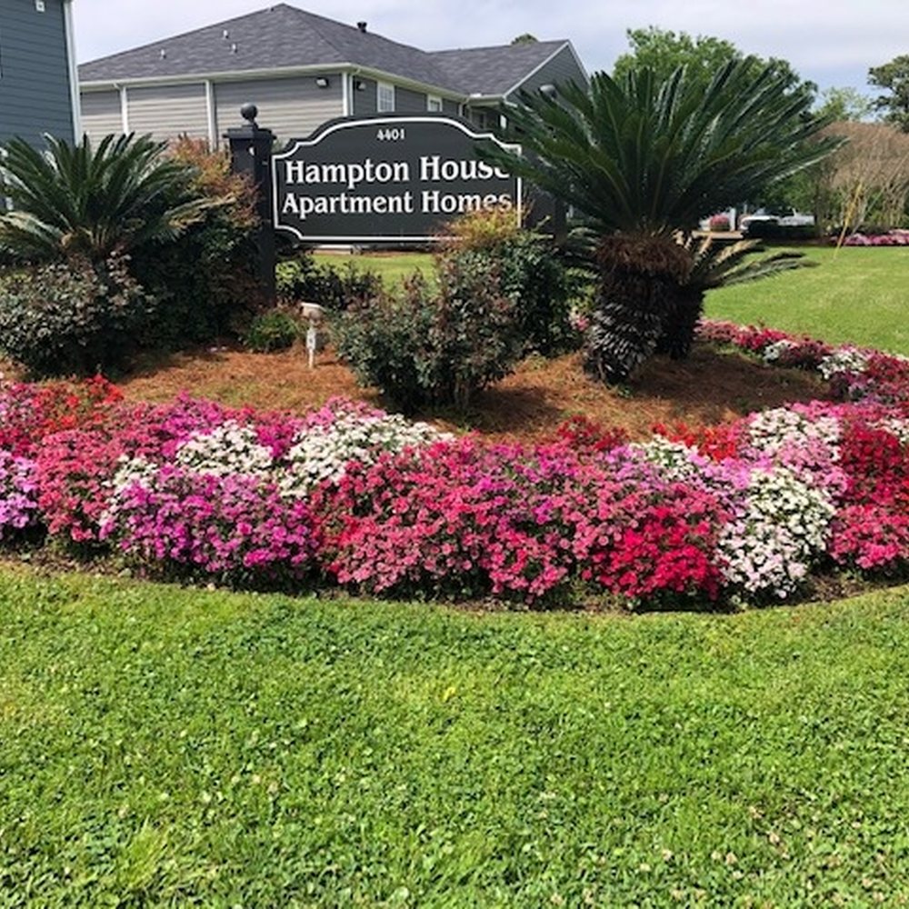 Colorful daylily and annual beds along a home with hanging baskets